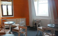 Theater unterm Dach mit  Blick auf die Sitzgruppen in der Gastronomie. Im Hintergrund 2 Fenster.